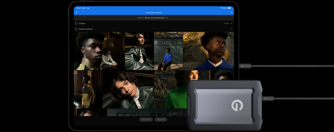 Un iPad Pro, face avant, orientation paysage, noir infini, branché à un disque dur externe USB-C avec un câble, écran affichant des photos de modèles en cours d’importation dans un dossier créé pour une séance photo publicitaire