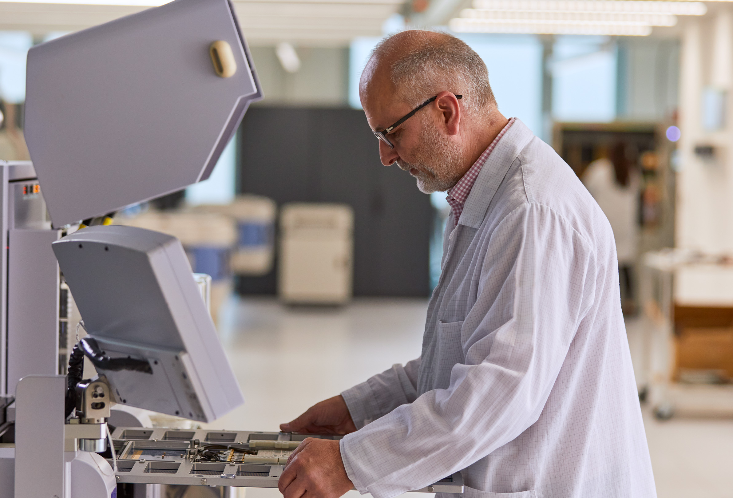 Funcionário da Apple de jaleco branco trabalha em um equipamento de engenharia. 