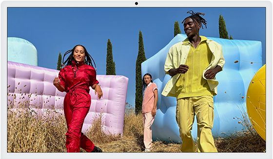 Three people in bright outfits, surrounded by colorful inflatable shapes