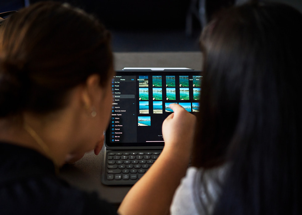 Two people shown from the behind use iPad to edit photos.