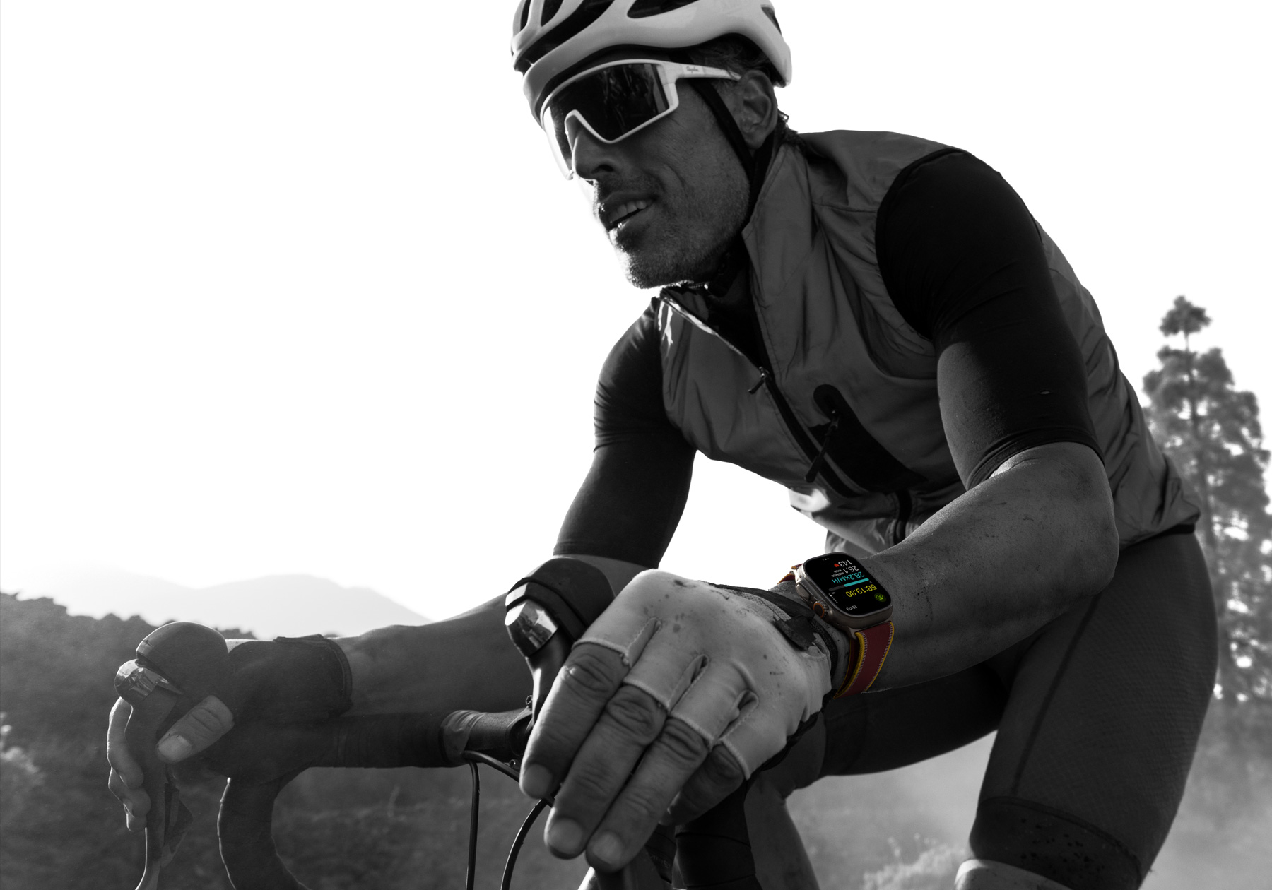 A person riding a road bike while wearing Apple Watch Ultra 4, screen shows cycling metrics