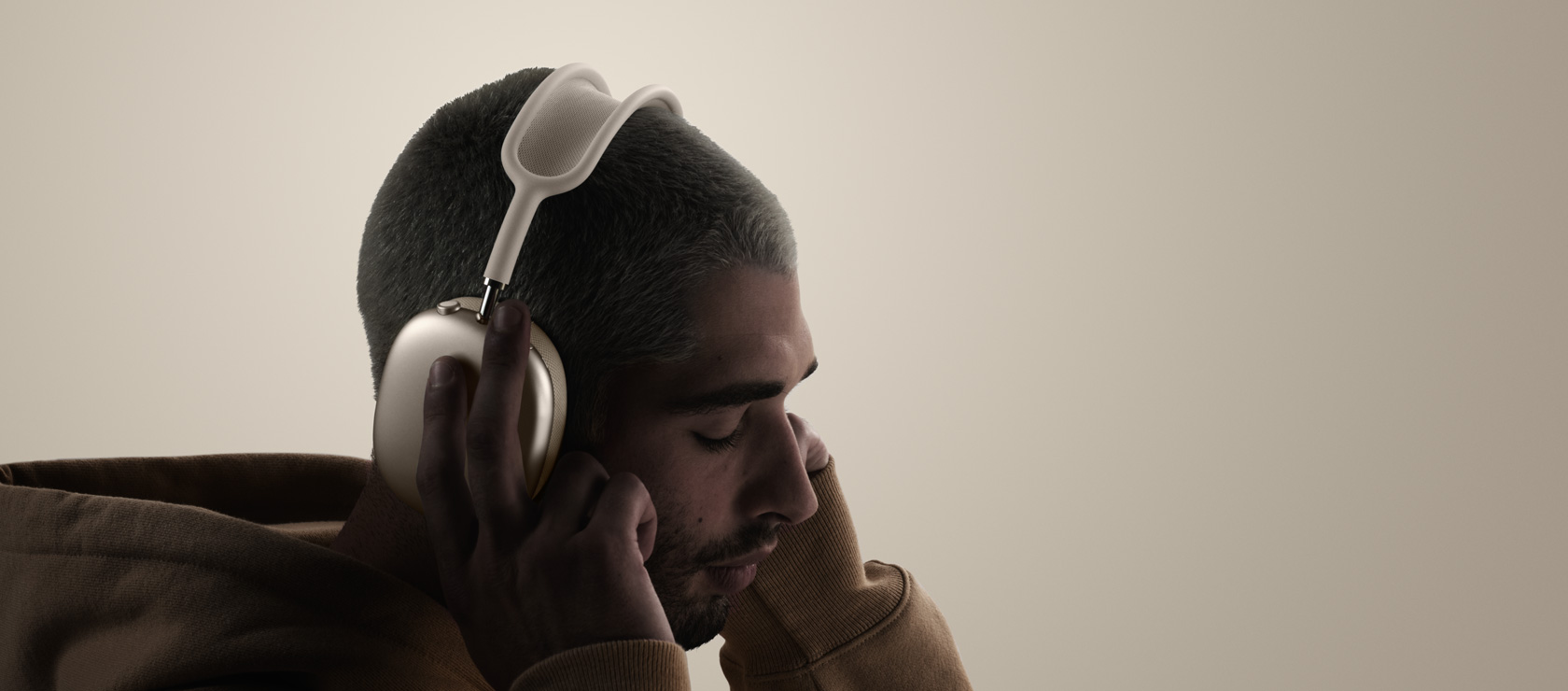 O persoană poartă căști AirPods Max 2, parte exterioară laterală, atingând pernițele auriculare