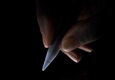 Потребител държи долната третина на Apple Pencil Pro между палеца и показалеца в позиция за писане.