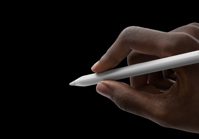 Ръка на потребител държи Apple Pencil Pro в позиция за писане. Върхът е насочен към интерфейс, който показва нова палитра с инструменти.