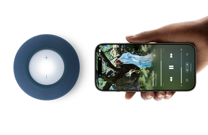 HomePod mini 2 and iPhone: A hand holds iPhone horizontally beside blue HomePod mini 2 for hand-off feature