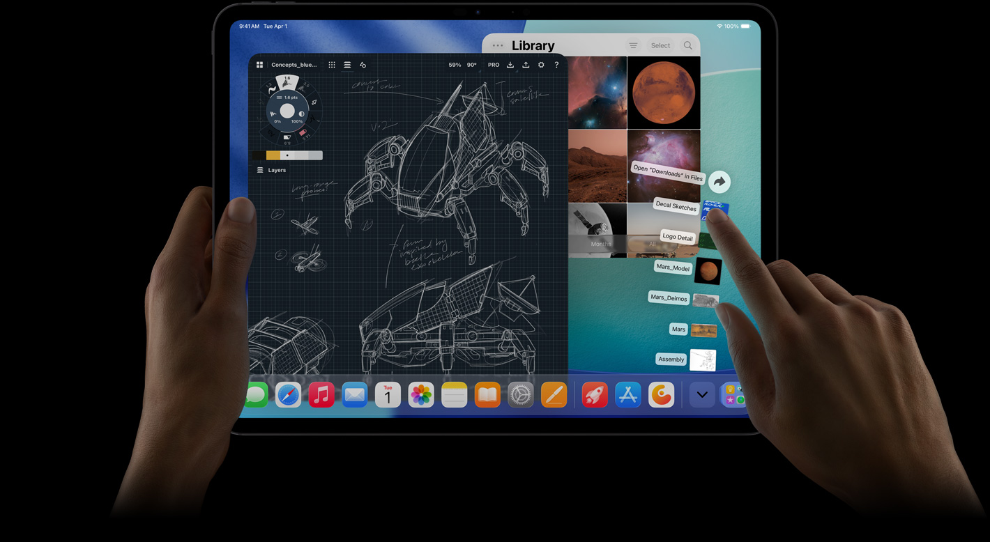 iPad Pro, pohľad spredu, orientácia na šírku, pravá ruka gestikuluje nad súbormi v priečinku Stiahnuté rozbalenými do tvaru vejára, na displeji je rozhranie systému iPadOS 26 s niekoľkými otvorenými apkami vrátane apky na úpravu fotiek s podrobnými plánmi robota, ručne písaných anotácií, viacerých fáz dizajnu a knižnice fotiek