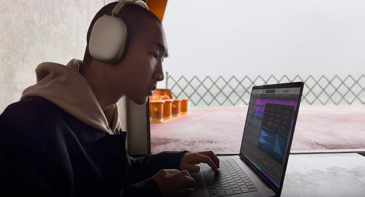 Una persona di profilo che indossa un paio di AirPods Max mentre usa Logic Pro su un MacBook Pro 16